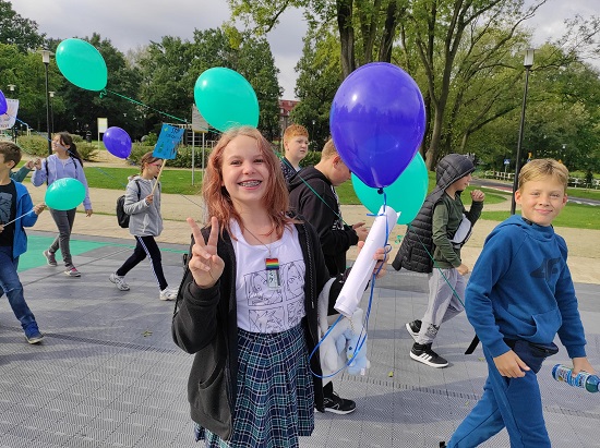 Na zdjęciu dzieci trzymające balony z hasłami profilaktycznymi