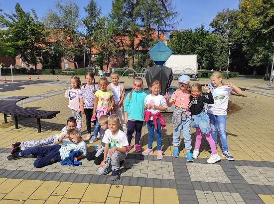Na zdjęciu dzieci pozujące do zdjęcia przy fontannie na placu rekreacyjnym