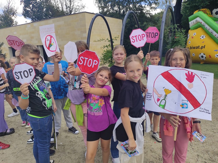 Na zdjęciu dzieci uczestniczące w marszu profilaktycznym trzymające w rękach hasła Stop uzależnieniom 